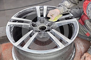 Master body repair man is working on preparing the surface of the aluminum wheel of the car for subsequent painting in the