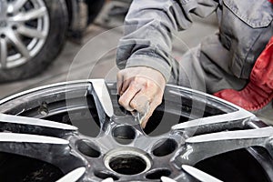 Master body repair man is working on preparing the surface of the aluminum wheel of the car for subsequent painting in the photo