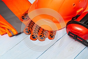 Master builder`s orange protective equipment stacked on blue boards before work