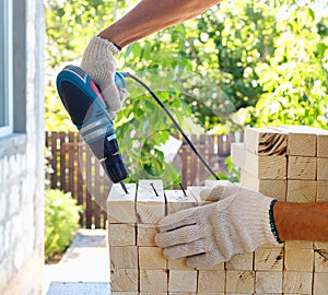 Master cabinetmaker makes wooden furniture with drill, nails, hammer. Handmade in home workshop