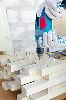 Master cabinetmaker makes wooden furniture with drill, nails, hammer. Handmade in home workshop