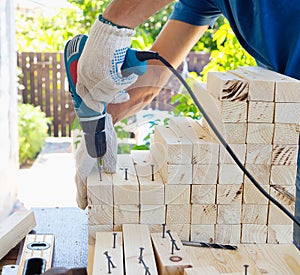 Master cabinetmaker makes wooden furniture with drill, nails, hammer. Handmade in home workshop