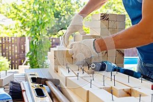 Master cabinetmaker makes wooden furniture with drill, nails, hammer. Handmade in home workshop