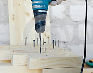 Master cabinetmaker makes wooden furniture with drill, nails, hammer. Handmade in home workshop