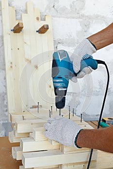 Master cabinetmaker makes wooden furniture with drill, nails, hammer. Handmade in home workshop