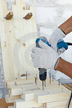 Master cabinetmaker makes wooden furniture with drill, nails, hammer. Handmade in home workshop