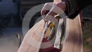 A master cabinetmaker marks with a compass on a half of a processed log for making a tool. Handicraft work. Individual