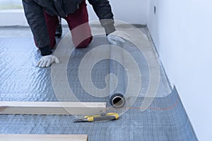 Master carpenter mounts pine wood floor - eco-friendly flooring. gluing the insulation layer under the lag on the