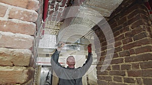 The master carries out measurements of ventilating channels on construction. The employee measures the ventilation