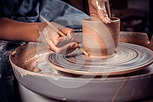 Master-ceramist creates a clay pot on a potter`s wheel. Hands of potter close up. Ancient craft and pottery handmade