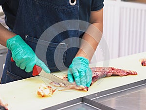 Master chef butcher is dissecting part of meat tenderloin , slicing membrane.