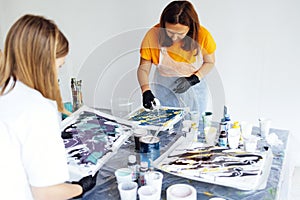 Master class on an Acrylic Fluid Pouring. Young women paint with liquid acrylic in an art workshop. Fluid Art