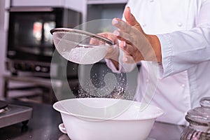 Master of confectionery sieving the flour preparing ingredients for pie