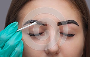 Master corrects makeup, it gives shape and color the eyebrows henna in a beauty salon, Spa.