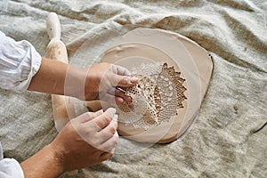 master craftsman rolls the clay on the table, transfers the napkin pattern to the clay mass