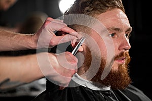 Master cuts hair and beard in the Barber shop. Hairdresser makes hairstyle using scissors and a metal comb.