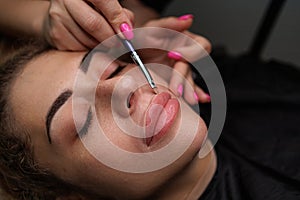 The master delicately applies tinting cream along the contour of the lips before permanent make-up. Delicate permanent lip makeup