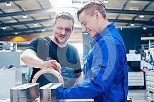 Master discussing a workpiece with his apprentice or trainee