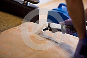 The master does a dry cleaning of the upholstery of a soft sofa using a professional washing vacuum cleaner. process photo