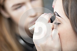 The master dyes the eyebrows brown to a beautiful young Caucasian girl. Close-up.