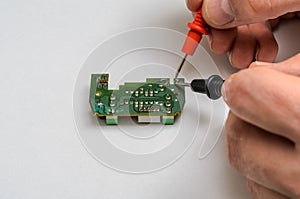 Master engineer tests and repairs microchip with multimeter