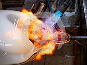 Master glassmaker heats a fire torch glass ball on a glass pipe