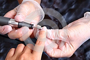 Master in gloves uses an machine to remove the cuticle photo