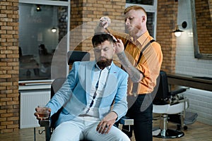Master hairdresser does hairstyle and style with scissors and comb. Portrait of stylish man beard. Hair Stylist and