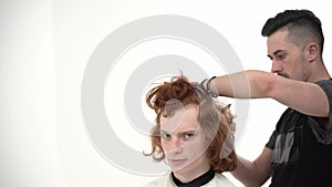 Master Hairdresser Doing Haircut to a Young Guy with Red Long Hair.