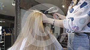 Master in a hairdresser dries her hair to a girl with a hairdryer and makes a styling