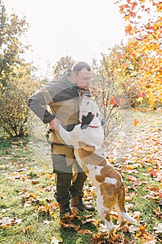 Master and her obedient dog playing together in autumn park