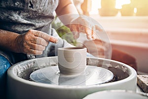 Master holds pot made of clay on potter wheel