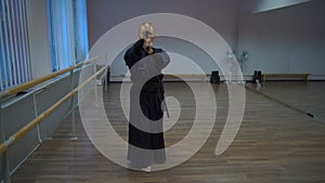 Master kendo performs the kata training with the catana sword in the sports hall with mirrors