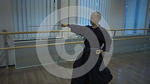 Master kendoka makes kata trains with katana sword in the sports hall morning