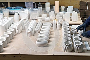 The master lays out Finished plaster products on the table: vases, figurines, bowls. Making and casting in the workshop decorative