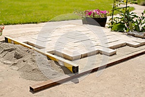 The master lays paving stones in layers. Garden brick pathway paving. Laying concrete paving slabs in house courtyard on sand