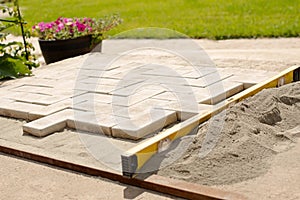 The master lays paving stones in layers. Garden brick pathway paving. Laying concrete paving slabs in house courtyard on sand