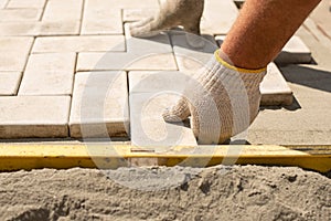 The master lays paving stones in layers. Garden brick pathway paving. Laying concrete paving slabs in house courtyard on sand