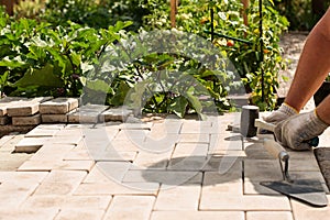 The master lays paving stones in layers. Garden brick pathway paving. Laying concrete paving slabs in house courtyard on sand