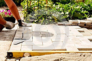 The master lays paving stones in layers. Garden brick pathway paving. Laying concrete paving slabs in house courtyard on sand