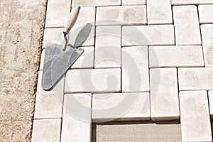 The master lays paving stones in layers. Garden brick pathway paving. Laying concrete paving slabs in house courtyard on sand