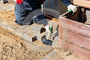 The master in lays paving stones in layers. Garden brick pathway paving by professional paver worker. Laying gray concrete paving