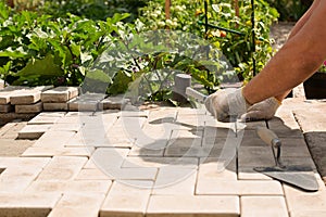 The master lays paving stones in layers. Garden brick pathway paving. Laying concrete paving slabs in house courtyard on sand