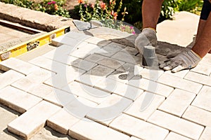 The master lays paving stones in layers. Garden brick pathway paving. Laying concrete paving slabs in house courtyard on sand