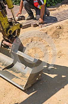 The master lays paving stones in layers, using hammer.