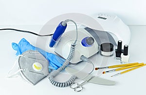 Manicure tools and equipment. A medical mask and rubber gloves lie next to the manicure machine.