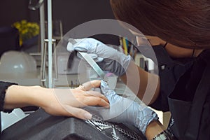 The master makes a manicure. Relaxing day at beauty salon. Manicurist master makes manicure on woman`s hand. Girl paint nails