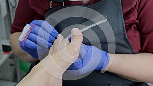 master makes a pedicure to a client in a beauty salon, using a foot nail file, peeling the skin of the feet. Close up