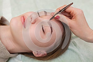 Master makeup corrects, and gives shape to pull out with forceps previously painted with henna eyebrows in a beauty salon.