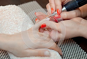 The master of the manicure saws and attaches a nail shape during the procedure of nail extensions with gel in the beauty salon. photo